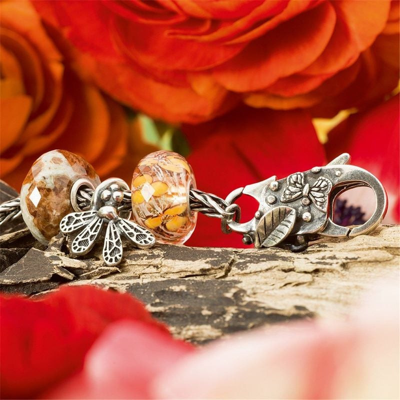 Fermoir papillon Trollbeads en argent sur bracelet de perles, décoré de roses orange et fond de bois