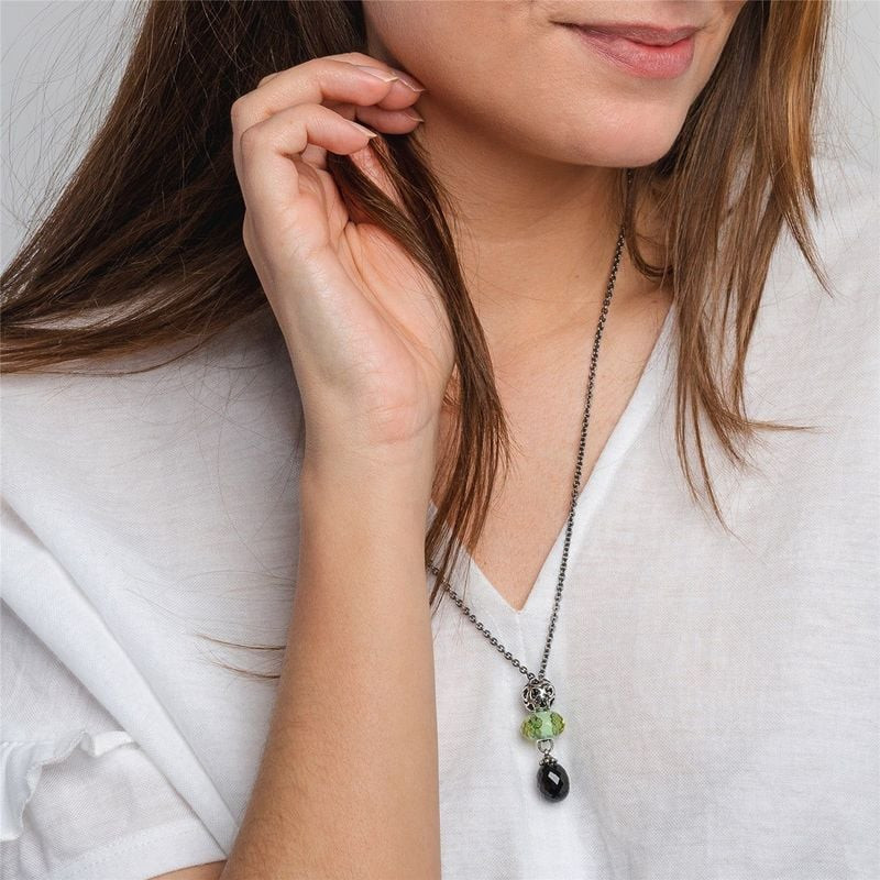 Femme en haut blanc portant un long collier Trollbeads en argent avec pendentif en onyx noir