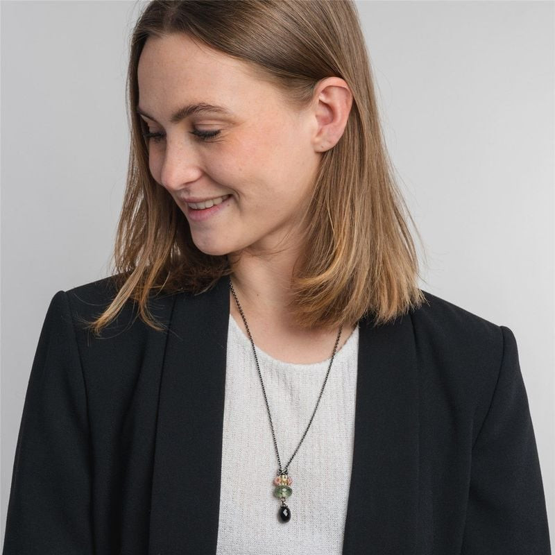 Femme en blazer noir portant un long collier Trollbeads en argent avec des perles vertes et onyx