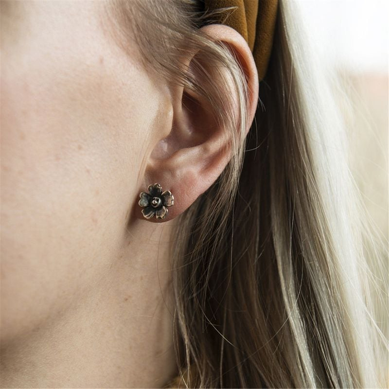 Puce d’oreille Trollbeads Fleur Réjouie en argent portée sur une oreille, cheveux blonds et bandeau 