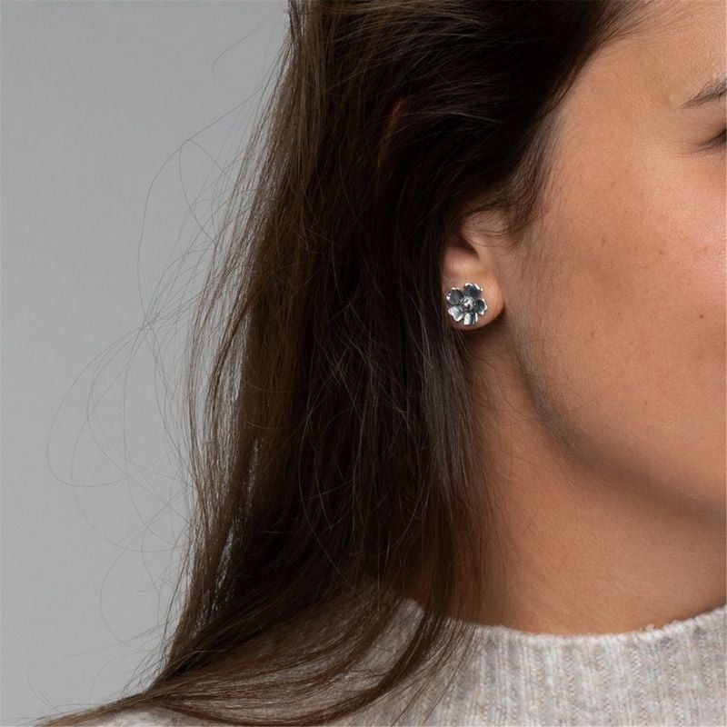 Vue de profil d'une oreille portant la boucle d'oreille puce fleur en argent Trollbeads Fleur Réjoui