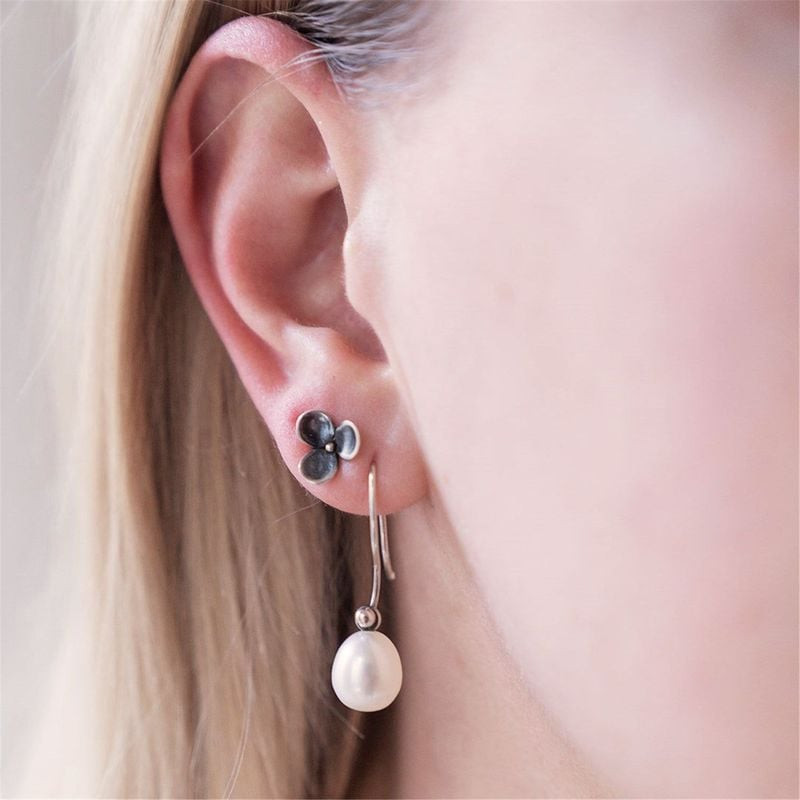 Vue rapprochée d'une oreille avec une boucle d'oreille goutte Trollbeads en perle blanche ovale et u