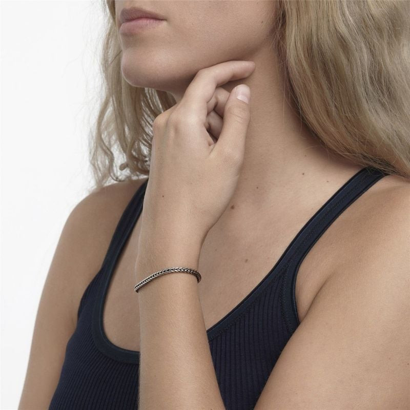 Gros plan du bras et du poignet d'une femme portant le bracelet Trollbeads en argent.