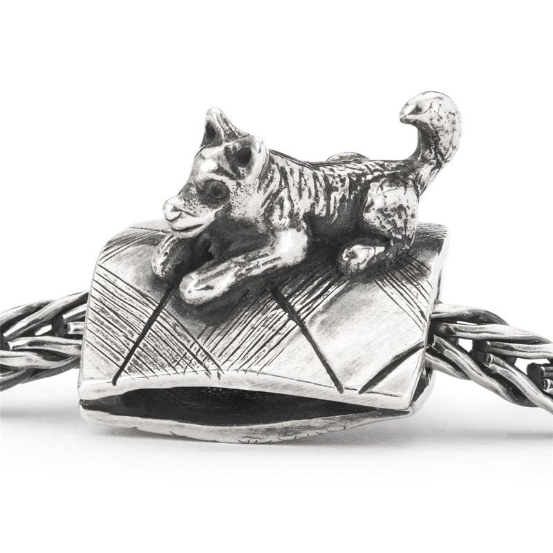 Gros plan du charm chien Trollbeads en argent sur une chaîne tressée, détails du tapis gravé