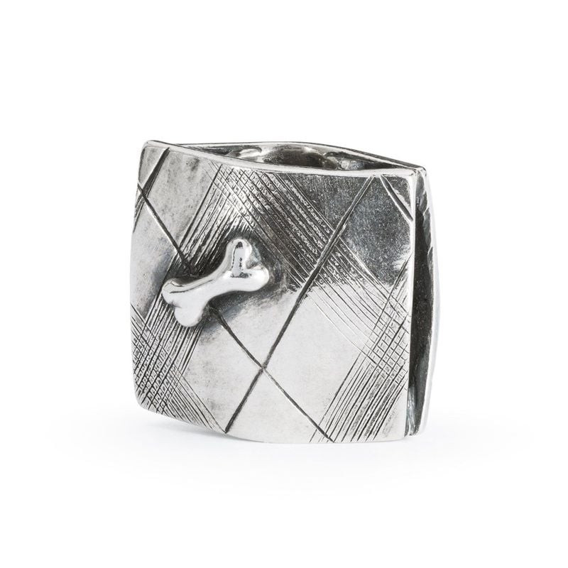 Revers du charm Trollbeads en argent montrant un os posé sur un tapis finement gravé à croisillons