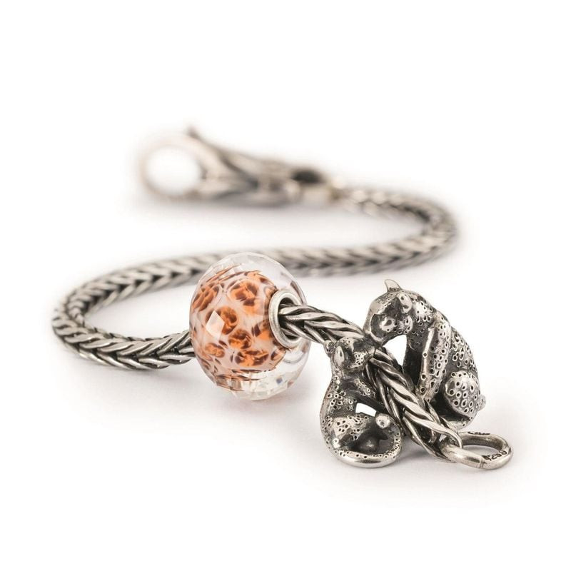 Charm léopard Trollbeads sur une chaîne en argent près d'une perle en verre rose facettée, poinçon 9