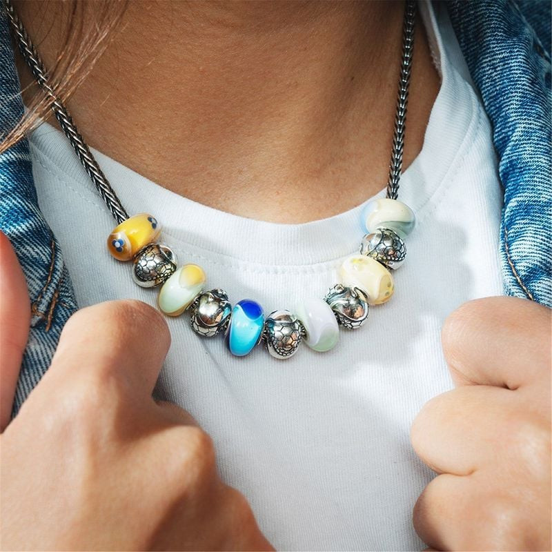 Assortiment de charms Trollbeads dont la PERLE TATOU ARGENT TROLLBEADS sur un collier