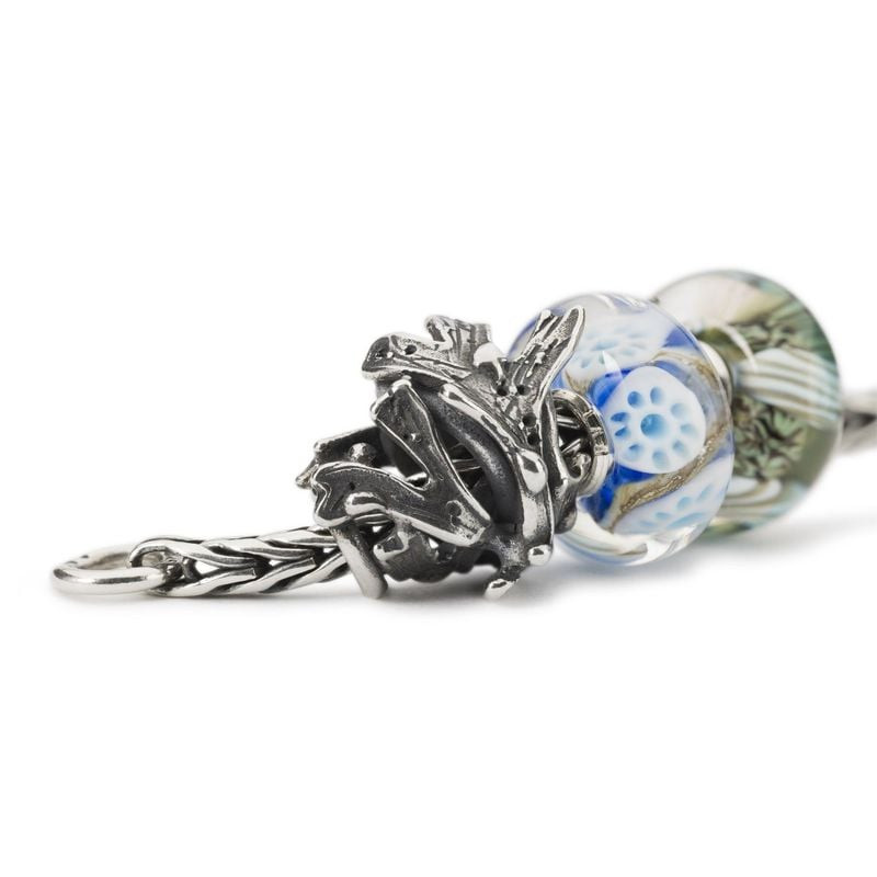 Gros plan de la perle de charme TROLLBEADS Algue Argenté avec des perles en verre bleu sur un bracel