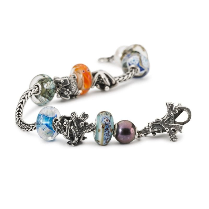 Une collection de perles Trollbeads, dont la perle ALGUE ARGENTÉ, disposée sur un bracelet en argent