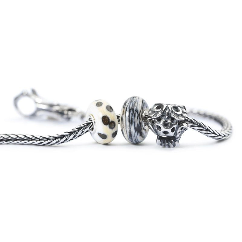 Perle de charme hibou Sage Hibou portée sur un bracelet Trollbeads à côté de perles en verre blanche