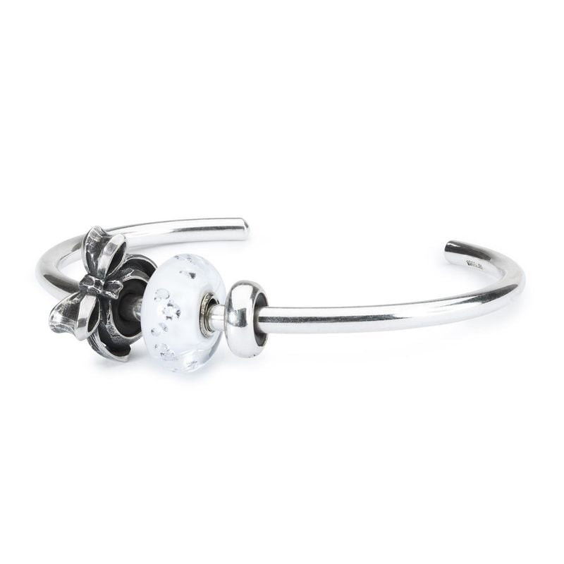Espaceur Nœud Trollbeads en argent sur un bangle près d'une perle de verre blanche, montrant comment