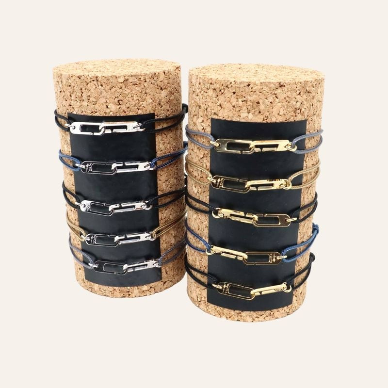 Bracelets Osmose présentés sur rouleaux de liège, maillons argentés et dorés sur cordons bleu marine