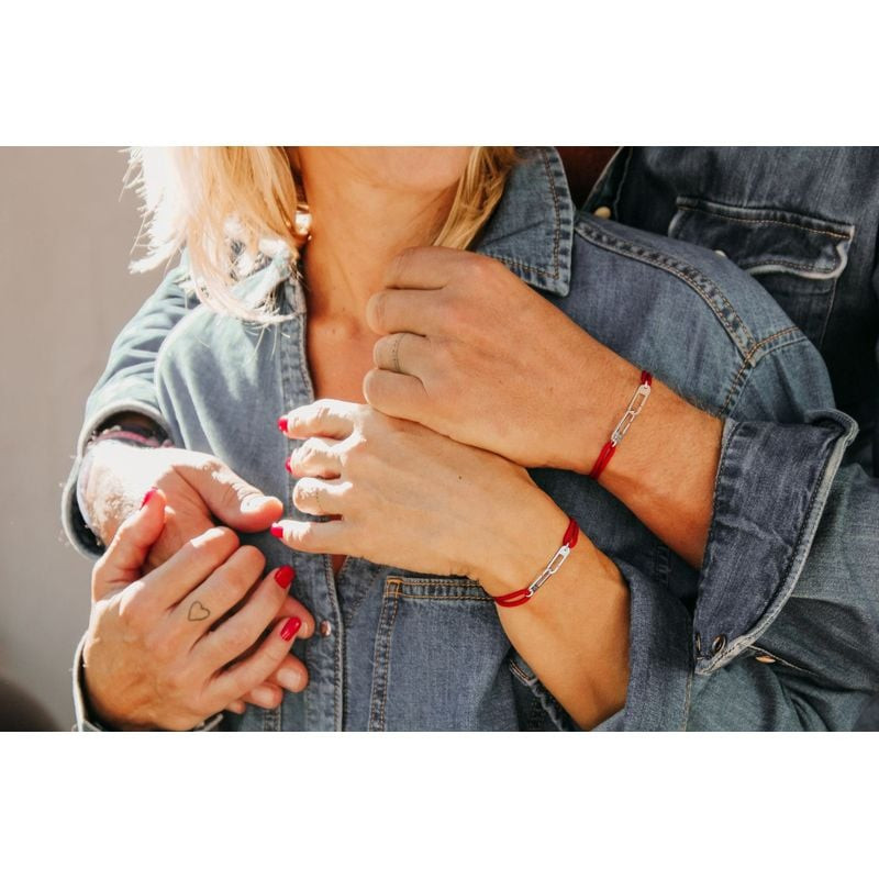 Gros plan sur deux mains portant des bracelets Osmose assortis en paracorde rouge et anneaux en arge