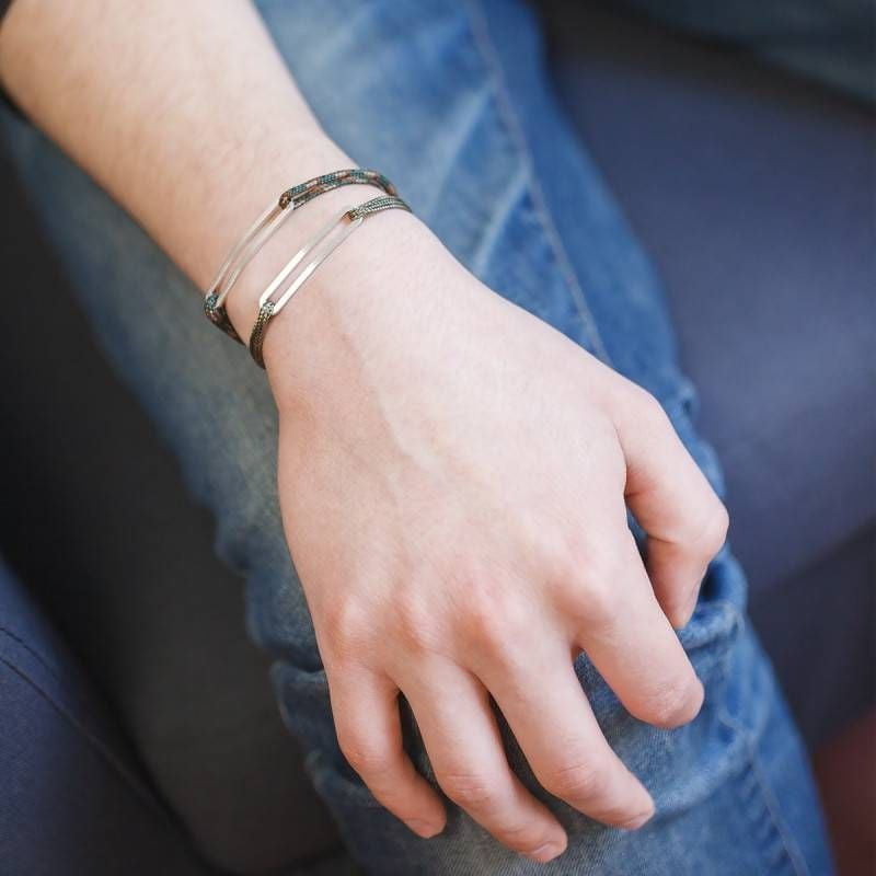Bracelets Figaro en paracorde kaki L'Avare avec barres en argent brossé empilés au poignet d'un homm