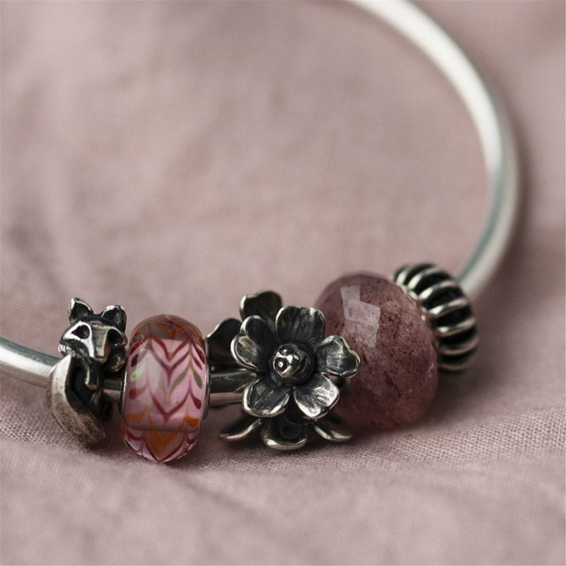 Breloque fleur en argent Trollbeads Fleur Réjouie portée sur un bracelet avec perles en verre rose e