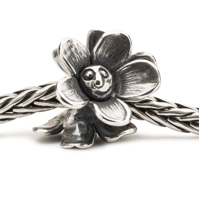 Breloque fleur argentée Trollbeads Fleur Réjouie enfilée sur une chaîne de bracelet tressée en argen