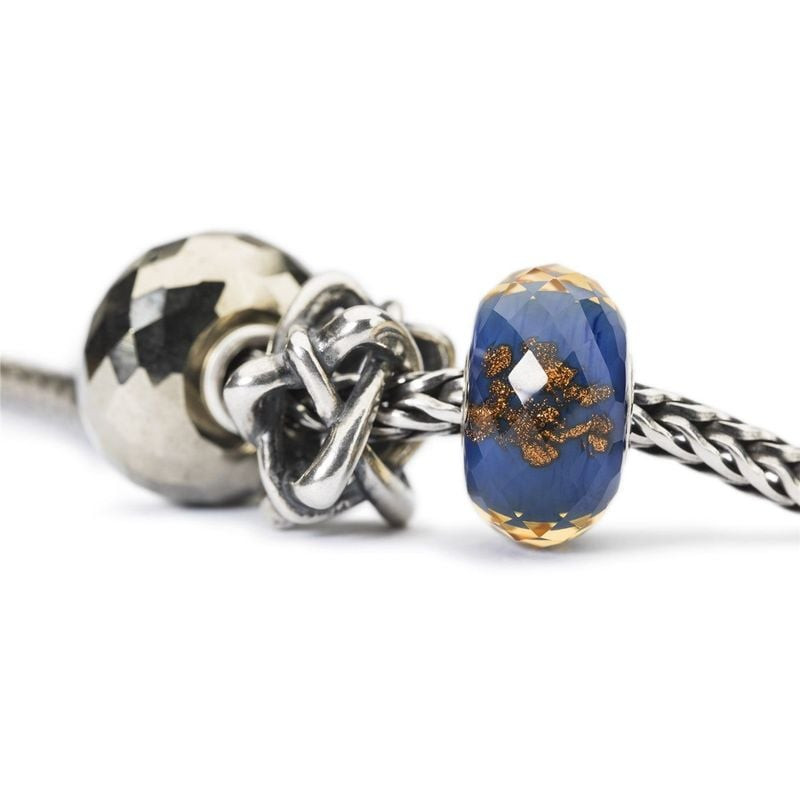 Gros plan sur la perle en argent Trollbeads Come Together aux cœurs entrelacés, à côté de perles en 