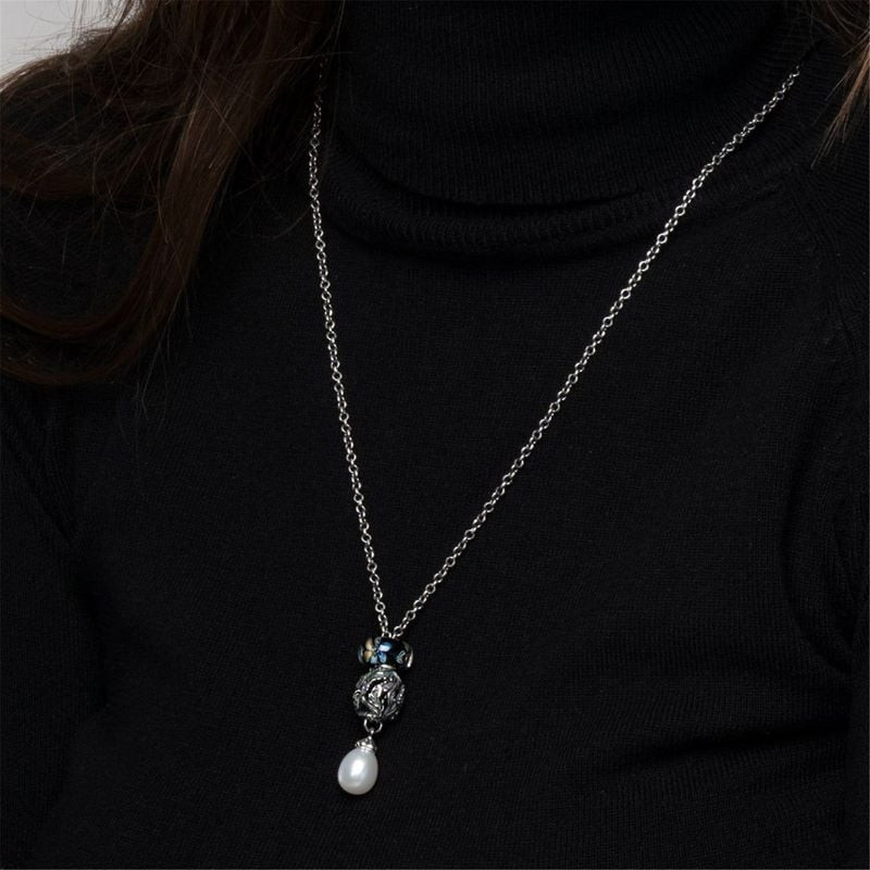 Perle argentée Étendue sauvage Trollbeads portée sur un long collier avec perle papillon en verre et