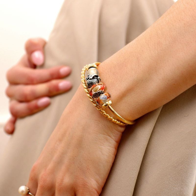 Femme portant un jonc Trollbeads en or et des charms, dont la perle coquille d'huître en argent au p