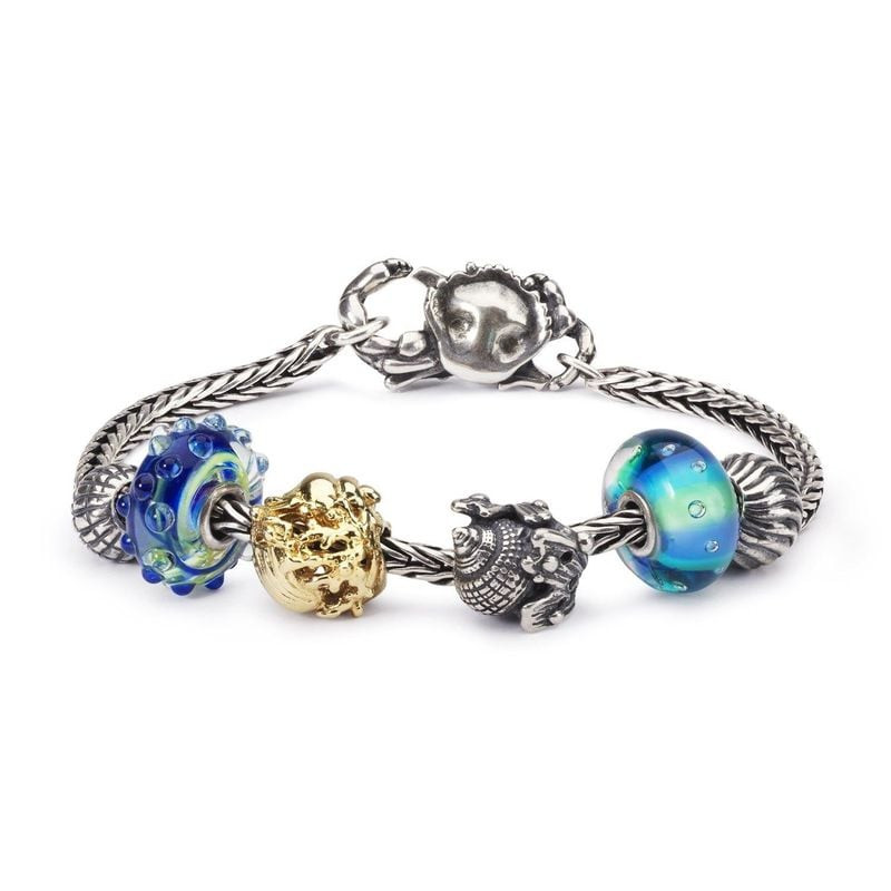 Charme Trollbeads Conque Coquillage Argenté en argent 925 posé sur une algue, ambiance marine et ser