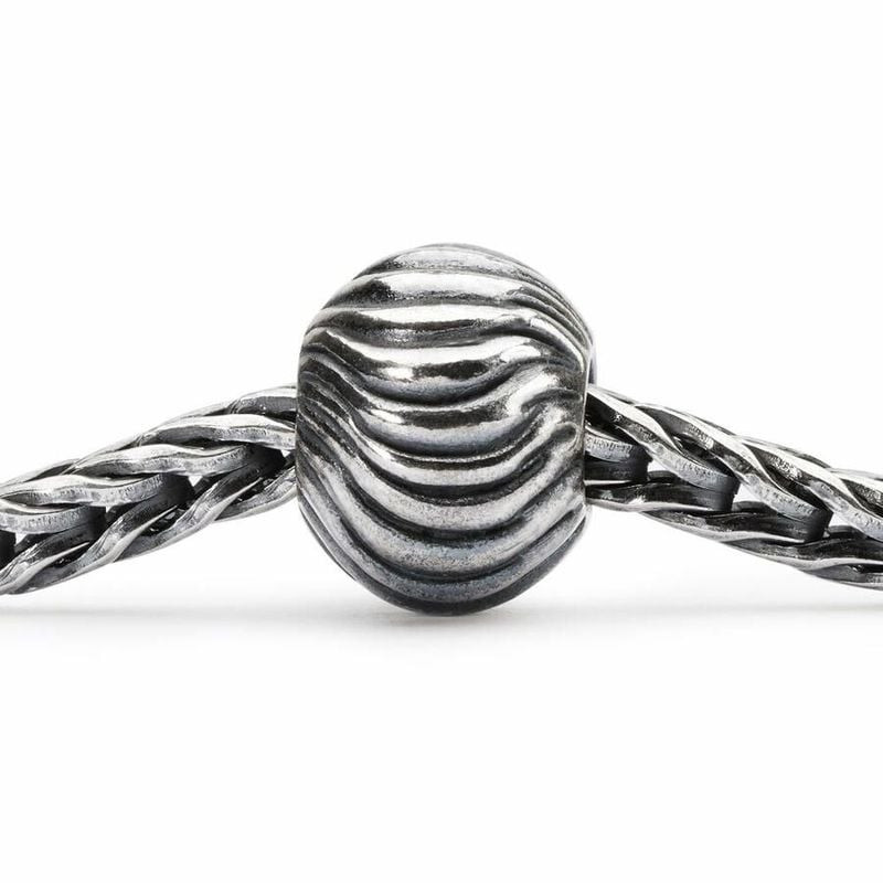 Perle Trollbeads Ondulations en argent, enfilée sur une chaîne de bracelet tressé, texture ondulée.