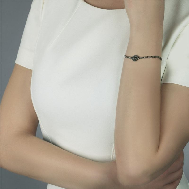 Femme portant la perle Trollbeads Poisson volant en argent sterling sur un bracelet fin en argent av
