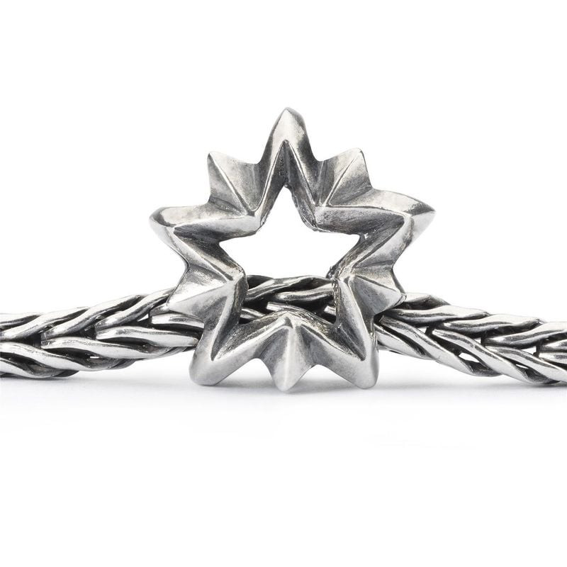 Détail macro du charm Trollbeads Étoile du berger en argent sterling 925‰ enfilé sur une chaîne tiss