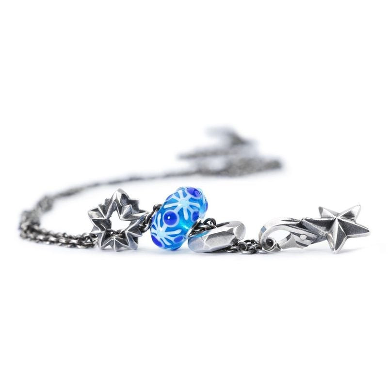 Charm Trollbeads Étoile du berger en argent à côté d'une perle en verre bleu sur une chaîne argentée