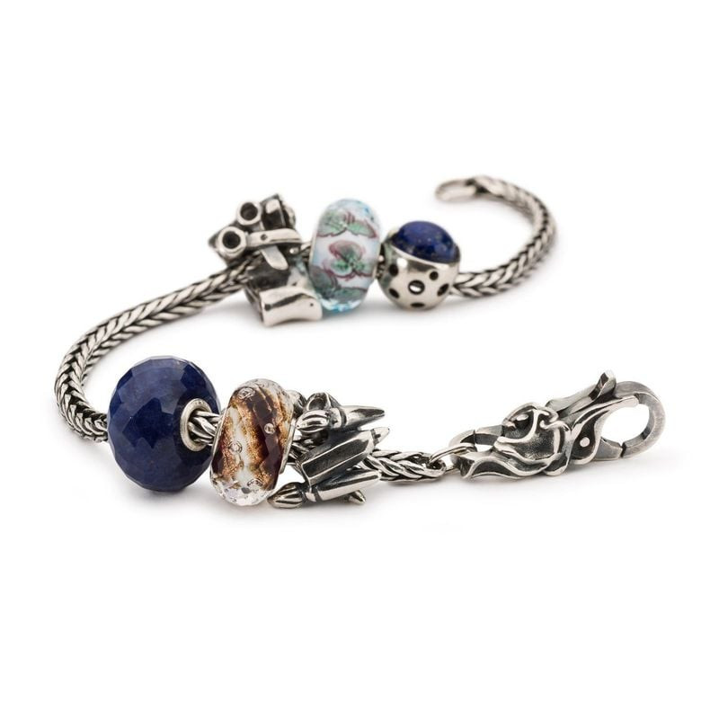 Assortiment de charms Trollbeads dont la perle Berceau de la Connaissance sur un bracelet.