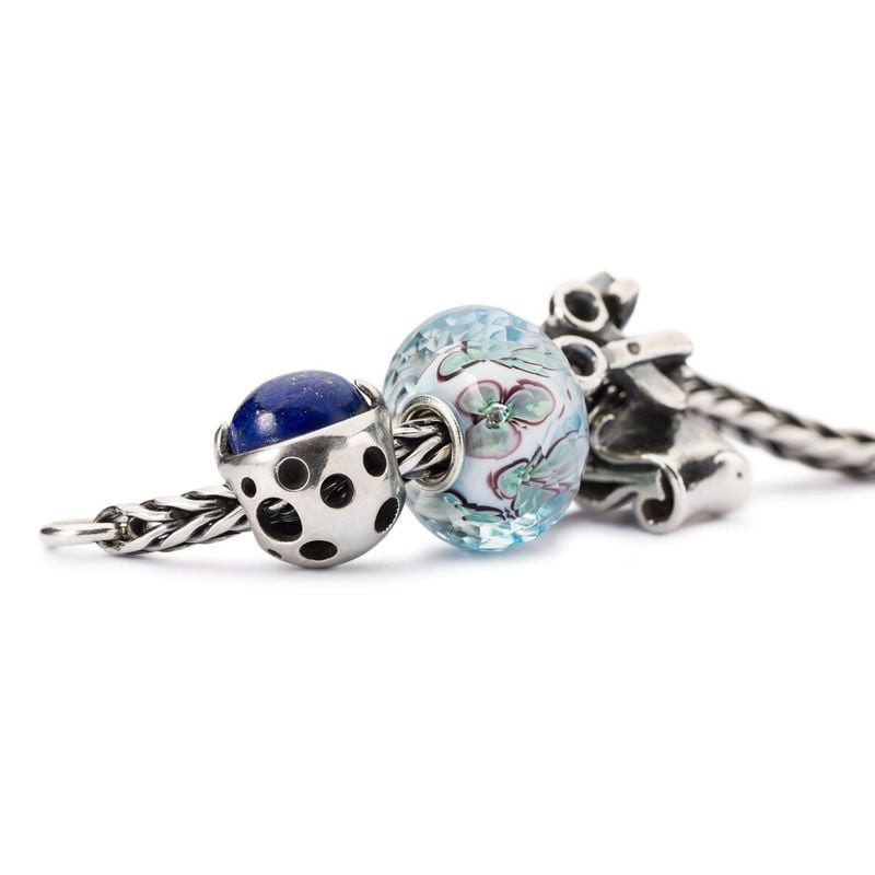 Gros plan de la perle Berceau de la Connaissance de TROLLBEADS avec d'autres perles Trollbeads sur u