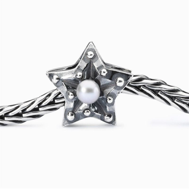 Gros plan de la perle TROLLBEADS Étoile de la concentration sur un bracelet en argent texturé.