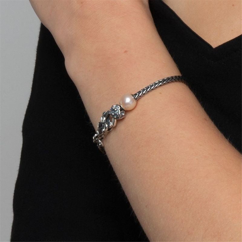 Charme perle rose Trollbeads Perle Rose sur bracelet en argent tressé porté avec des vêtements noirs
