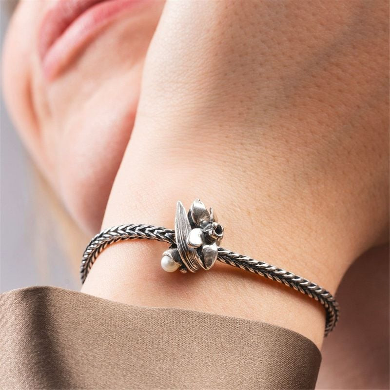 Gros plan sur la Perle Trollbeads Fleurs de naissance Narcisse Argenté, portée sur un bracelet Troll