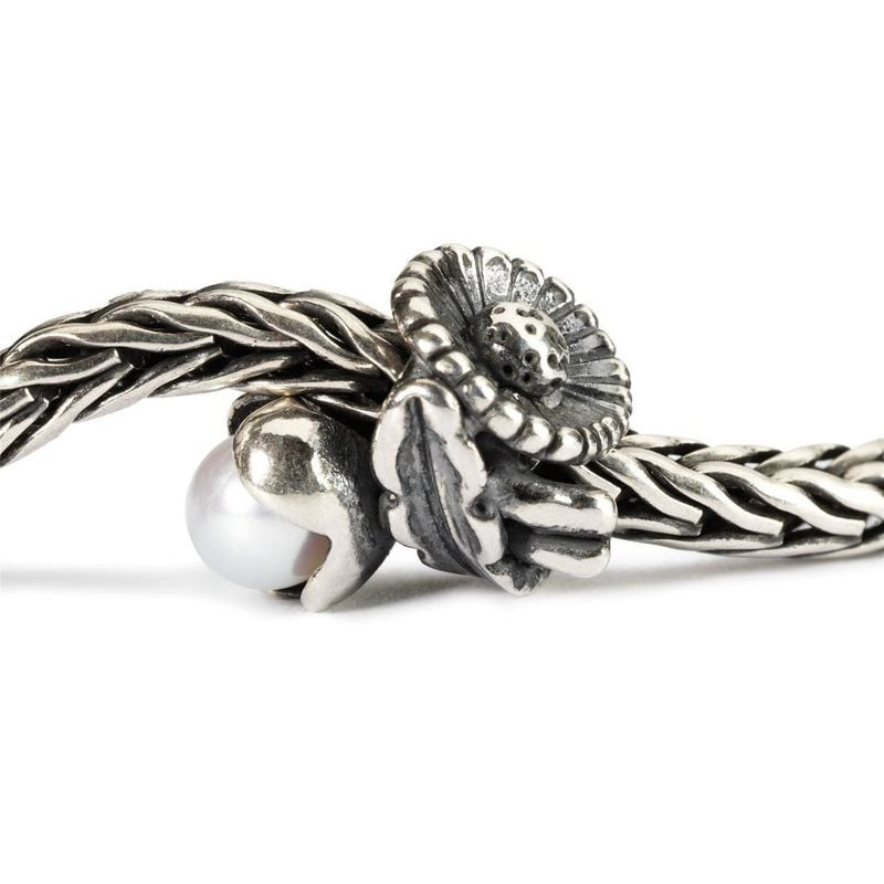Charm Trollbeads Marguerite d'avril enfilé sur une chaîne en argent tressée Trollbeads en gros plan