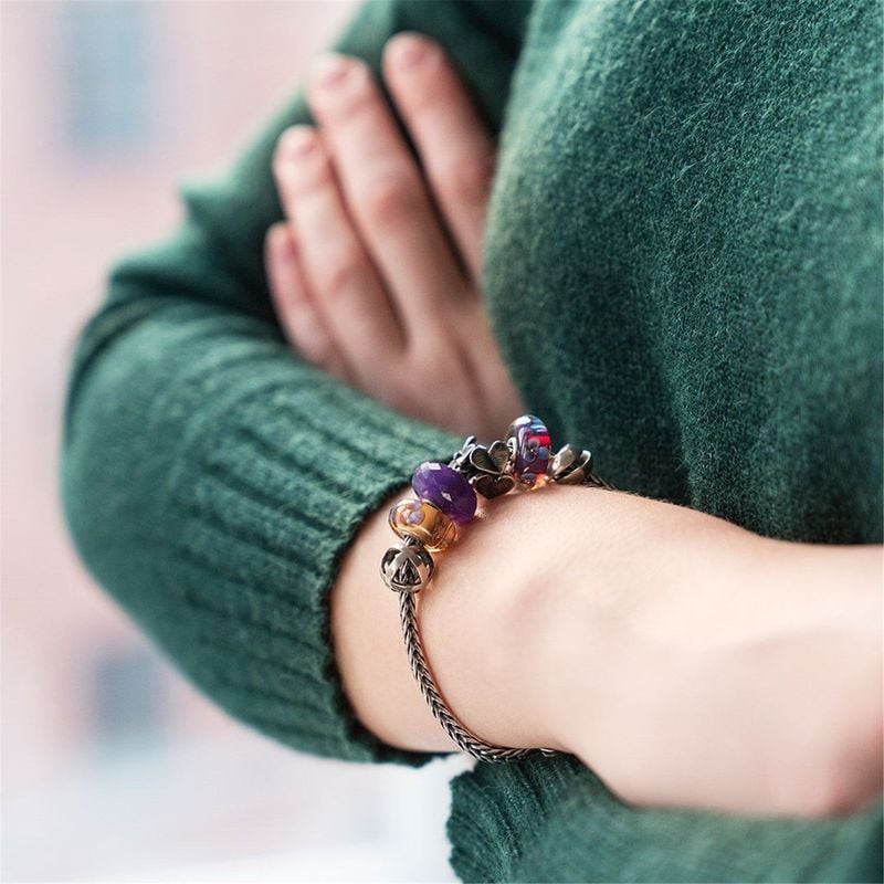 Bracelet Trollbeads avec la perle Violette de Février et des perles de verre colorées porté sur un p