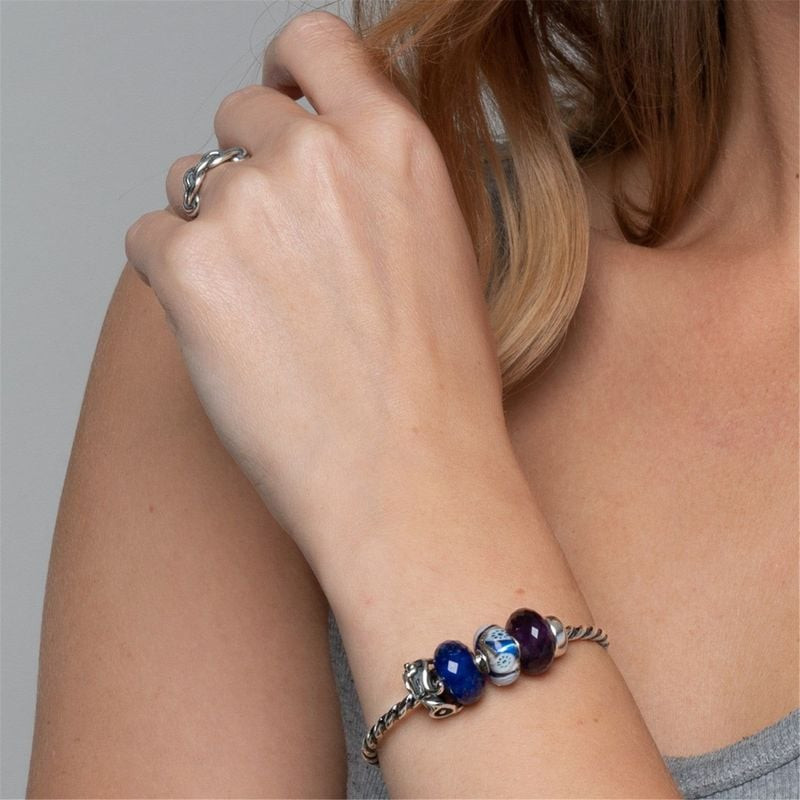 Modèle portant le jonc torsadé en argent Trollbeads avec des perles en verre bleu au poignet, main p