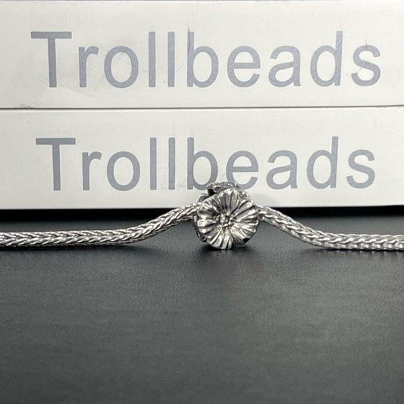 Pendentif Trollbeads Fantasy Rose Argenté posé sur un fond élégant, charme floral en argent sterling