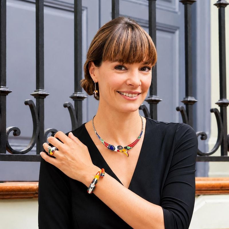 Femme souriante portant la bague en argent Toucan UNA STORIA, collier et bracelet assortis près d'un