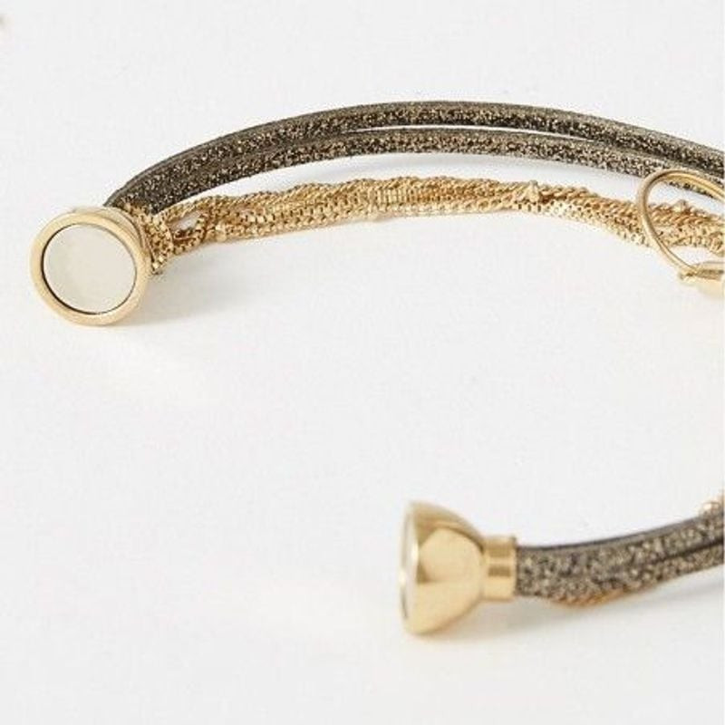 Gros plan sur le fermoir à boule dorée du bracelet Clover Noir et le détail du cuir noir scintillant