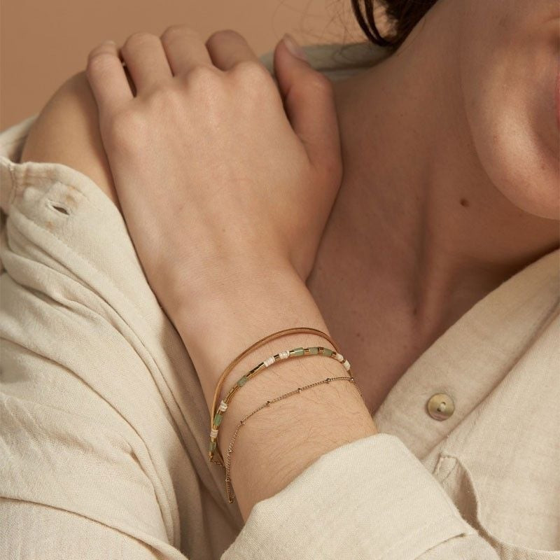 Femme portant le bracelet Appoline doré et jade FlowersforZoé superposé au poignet avec une chemise 