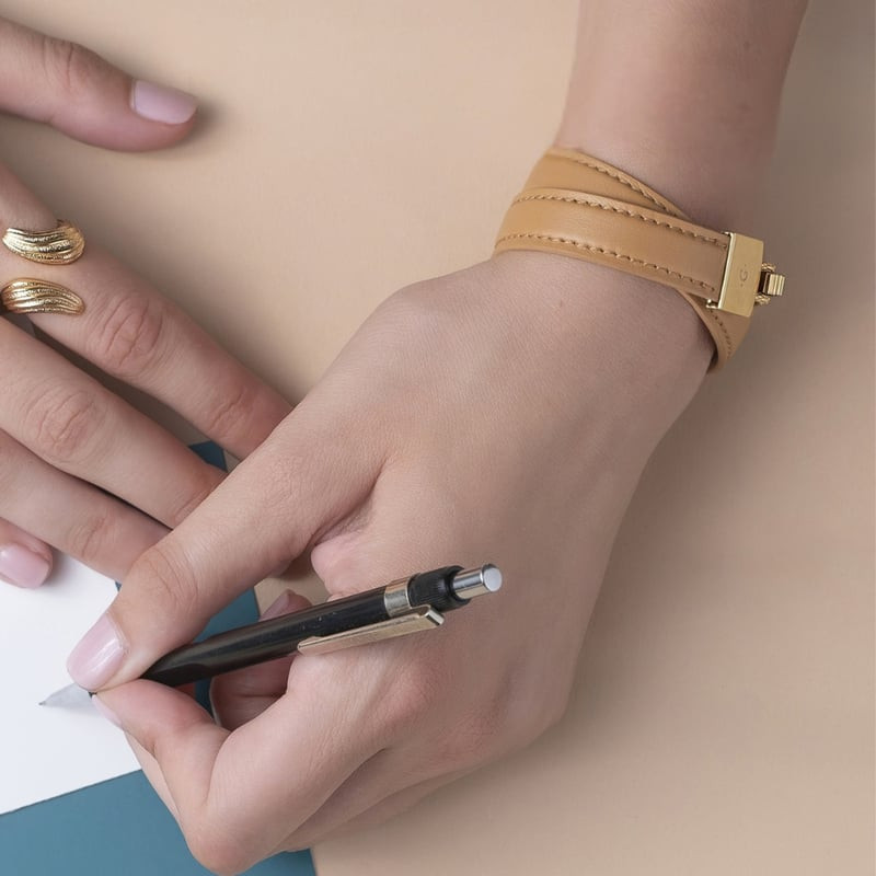 Photo lifestyle d'une main portant le bracelet double tour Les Georgettes Twist en cuir camel