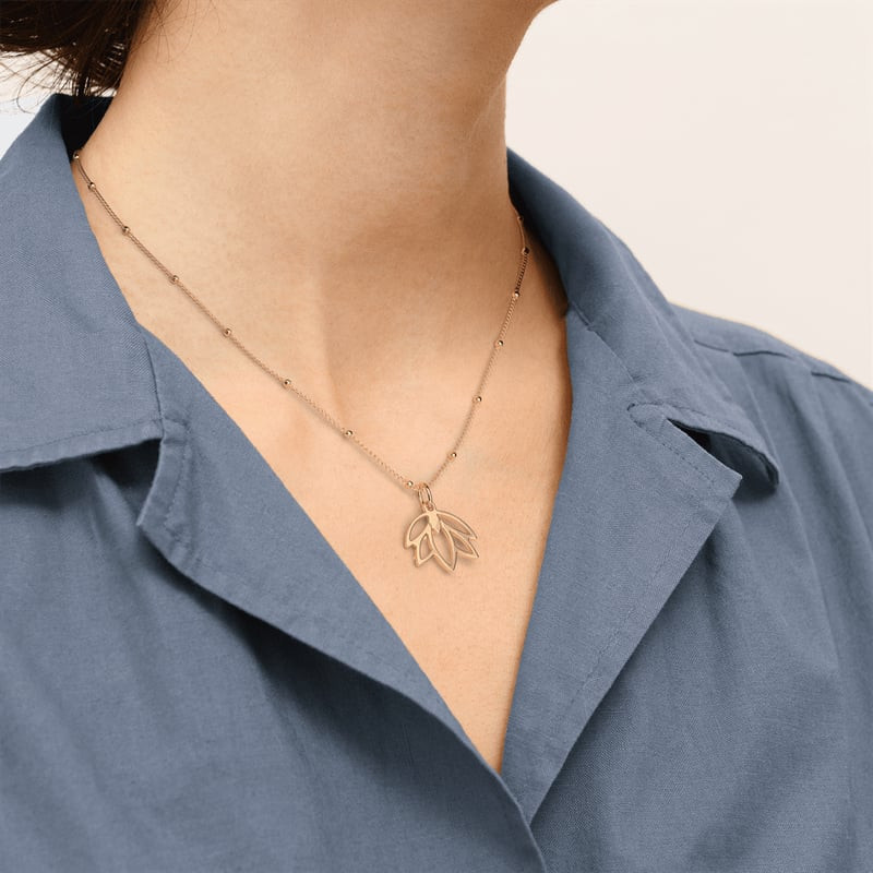 Mannequin portant le collier doré Les Georgettes Lotus avec pendentif fleur ajourée sur l'encolure d